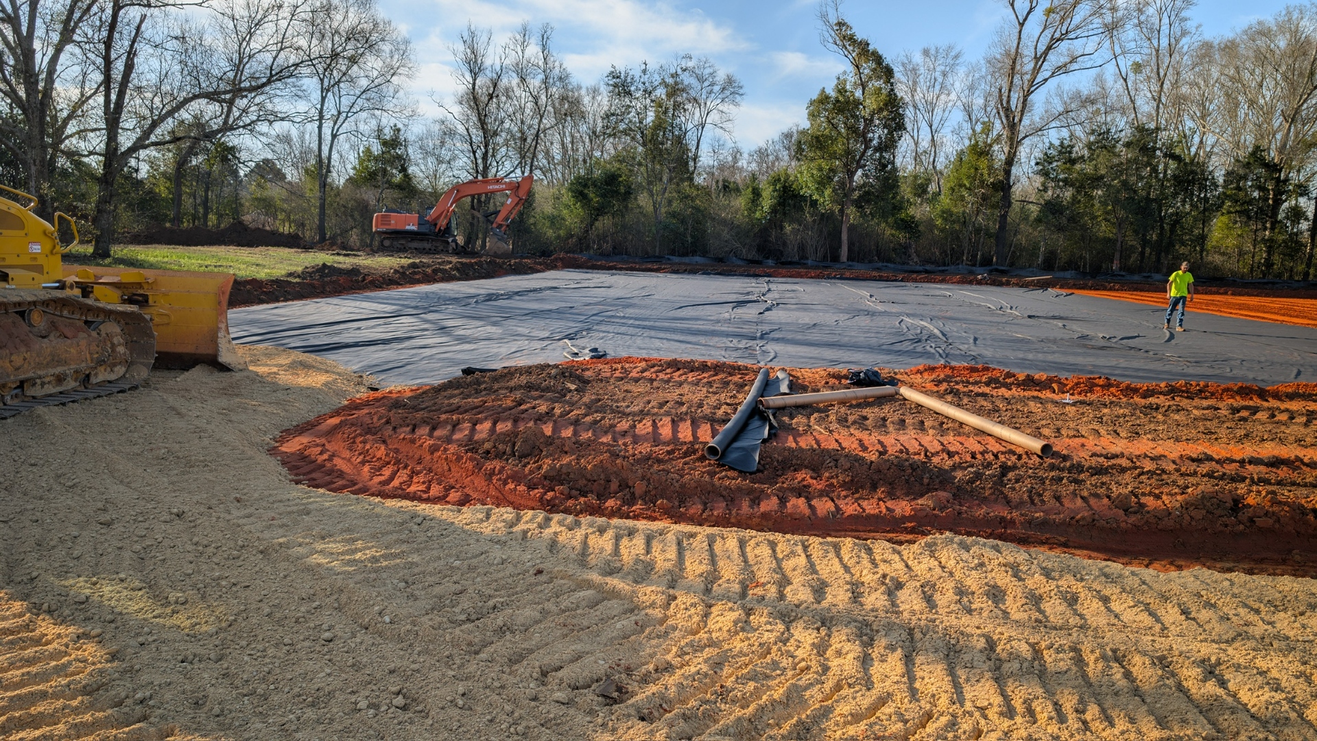 James Bros Excavating crew preparing a wide commercial site with geotextile and an excavator working subgrade