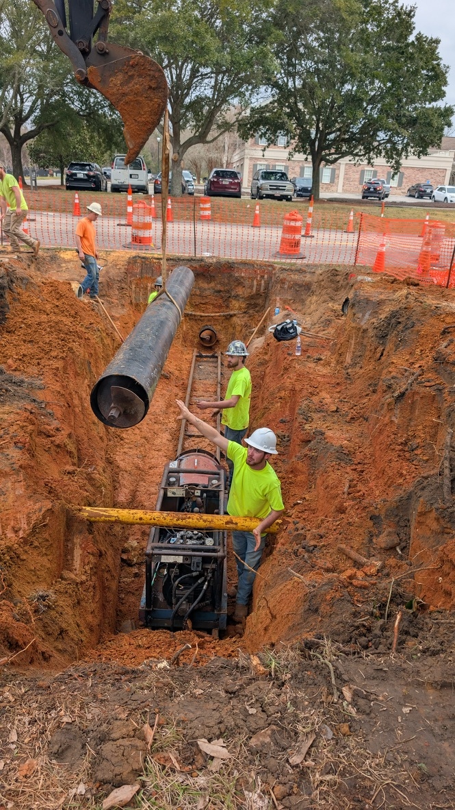 Crew working in an open excavation during a jack and bore utility installation