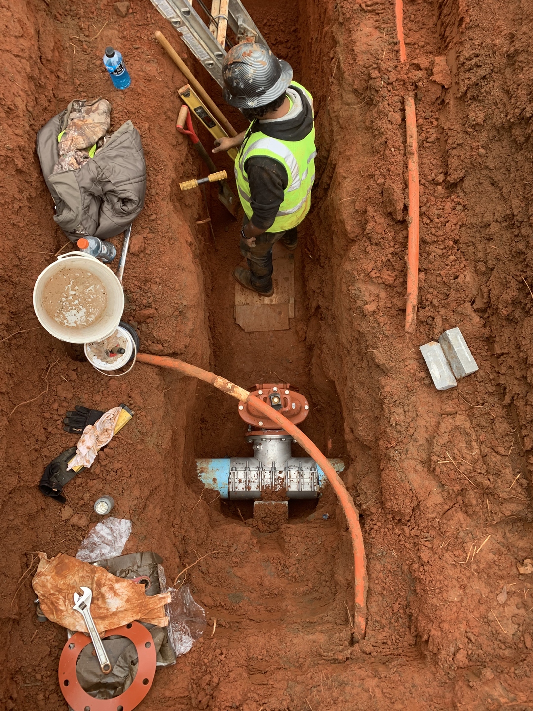 Crew member working in a utility trench on a water main connection